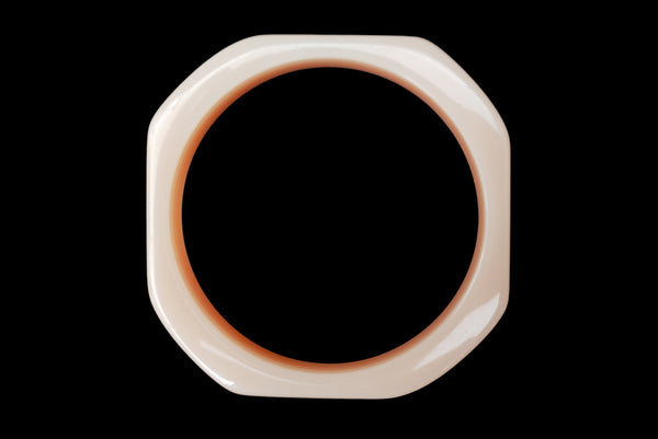 Horizontal top view of 1980s vintage orange and white square sliced polka dot, striped, and translucent solid three (3) bangle bracelet set. Showing the orange with white striped layered bangle alone.