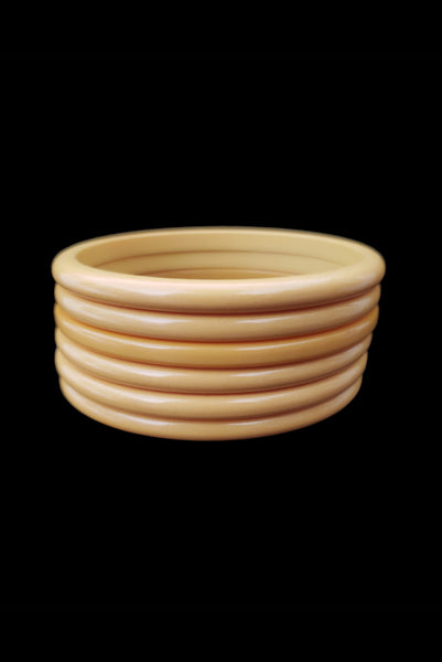 Vertical front view of 1930s vintage set of six (6) corn mustard yellow Bakelite spacer bangle bracelets.