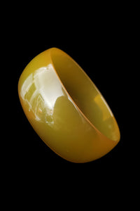 Vertical perspective view of 1940s vintage translucent chartreuse yellow green Bakelite bangle bracelet.