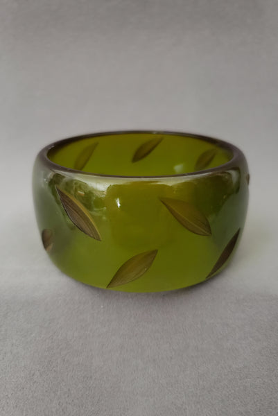 Vertical front view of 1930s vintage statement leaf carved prystal green Bakelite bangle bracelet.