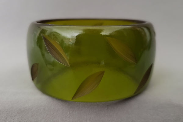 Horizontal front view of 1930s vintage statement leaf carved prystal green Bakelite bangle bracelet.