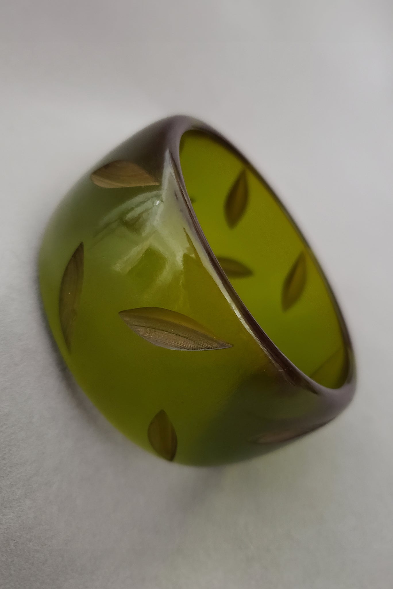 Vertical perspective view of 1930s vintage statement leaf carved prystal green Bakelite bangle bracelet.