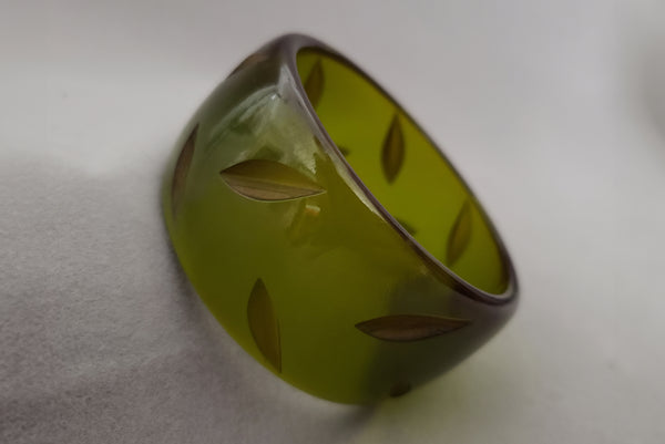 Horizontal perspective view of 1930s vintage statement leaf carved prystal green Bakelite bangle bracelet.