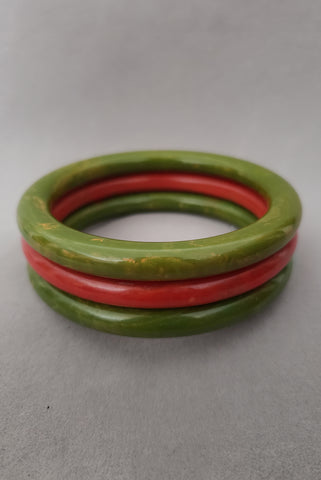 Vertical perspective view of 1950s vintage leaf green and tomato red Bakelite bangle three (3) bracelet set, by Avon.