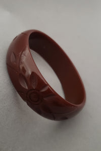 Vertical perspective view of 1940s vintage chocolate brown floral carved Bakelite bangle bracelet.