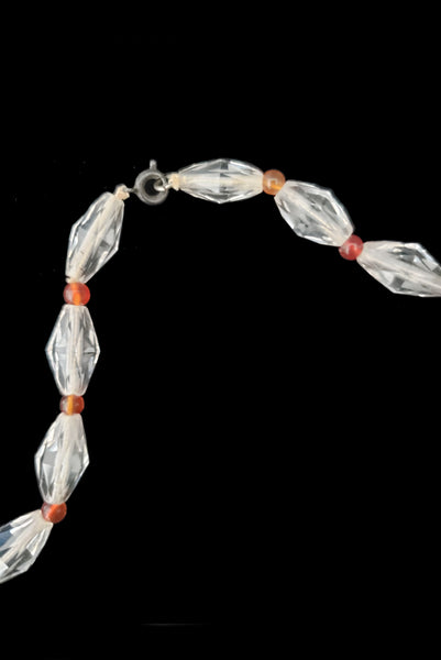 Detail view of 1920s vintage graduated bicone clear crystal bead necklace with orange amber colored round glass spacers. Showing a close-up of the spring ring clasp.