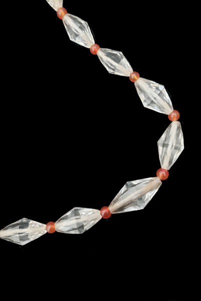 Detail view of 1920s vintage graduated bicone clear crystal bead necklace with orange amber colored round glass spacers. Showing a close-up of the necklace center front.