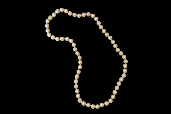Horizontal view of 1980s vintage cream faux pearl long beaded necklace.