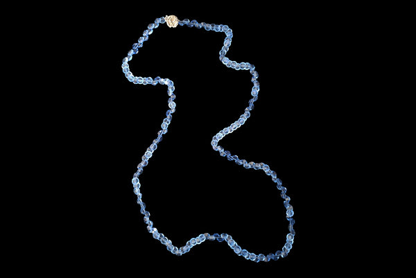 Horizontal front view of 1980s vintage blue faceted round crystal long beaded necklace with silver tone rose clasp.