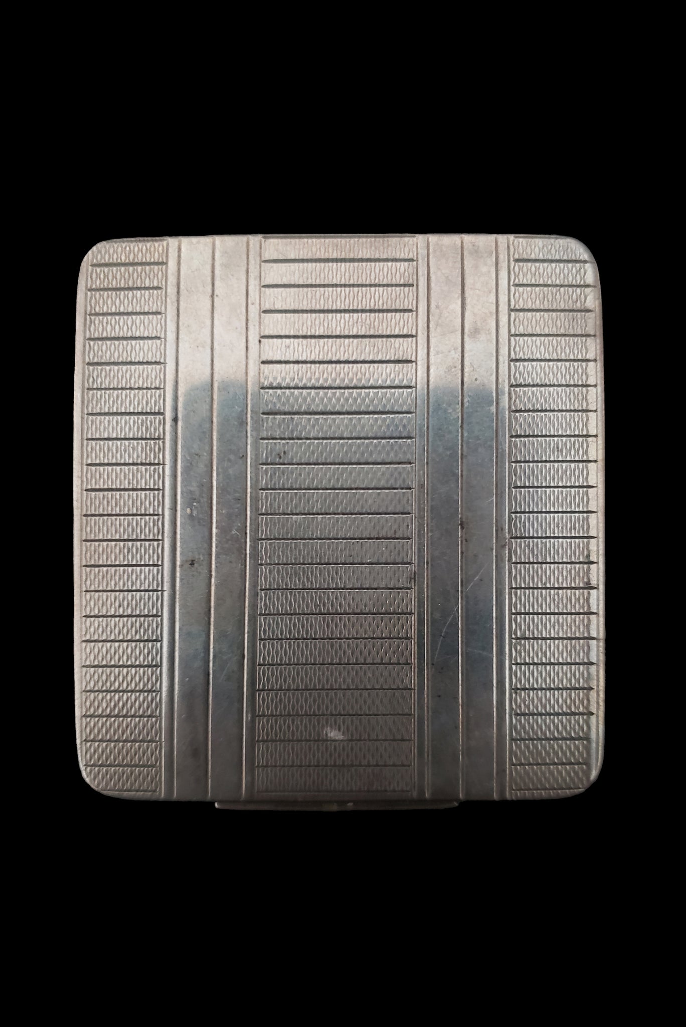 Vertical top view of 1920s vintage square silver tone stripe engraved make-up compact.