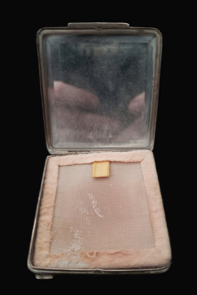 Vertical open view of 1920s vintage square silver tone stripe engraved make-up compact. Showing the mirror and screen covering the vintage powder.