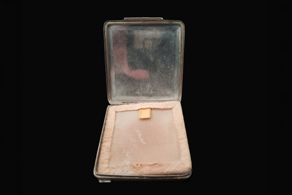 Horizontal open view of 1920s vintage square silver tone stripe engraved make-up compact. Showing the mirror and screen covering the vintage powder.