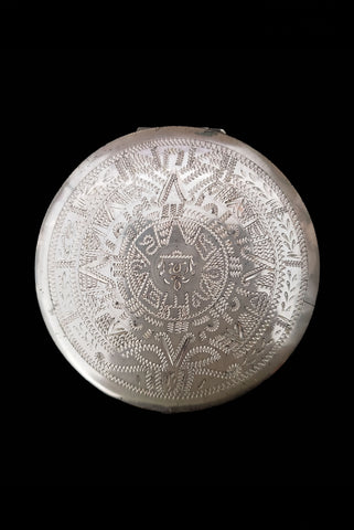 Vertical top view of 1950s vintage round sterling silver Aztec calendar engraved make-up compact.