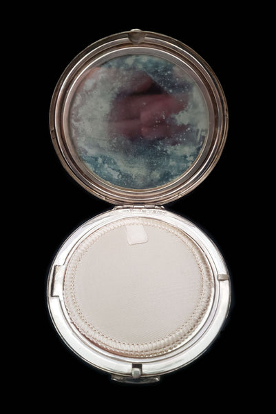 Vertical open view of 1950s vintage round sterling silver Aztec calendar engraved make-up compact. Showing the mirror that has gone cloudy from age.