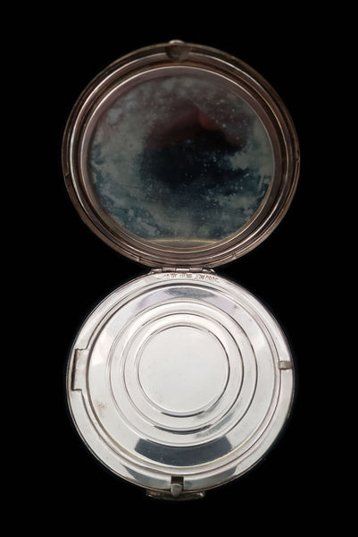Vertical open view of 1950s vintage round sterling silver Aztec calendar engraved make-up compact. Showing the powder puff removed, and the door to the powder compartment.