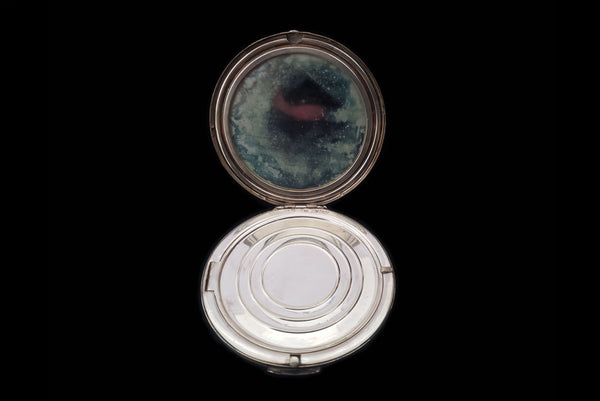 Horizontal open view of 1950s vintage round sterling silver Aztec calendar engraved make-up compact. Showing the powder puff removed, and the door to the powder compartment.