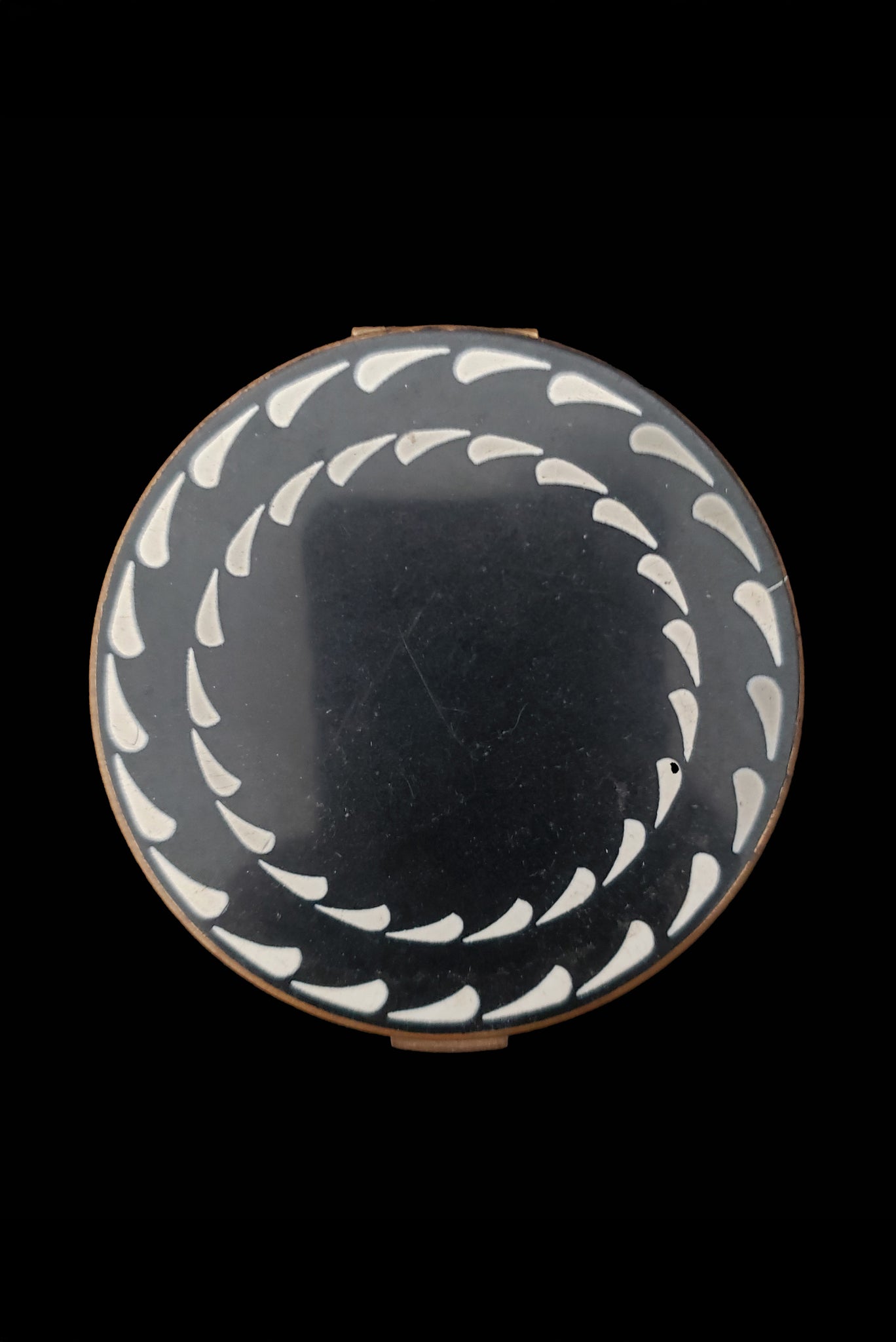 Vertical top view of 1930s vintage Art Deco black and white enamel round gold metal mesh make-up compact by Elgin.