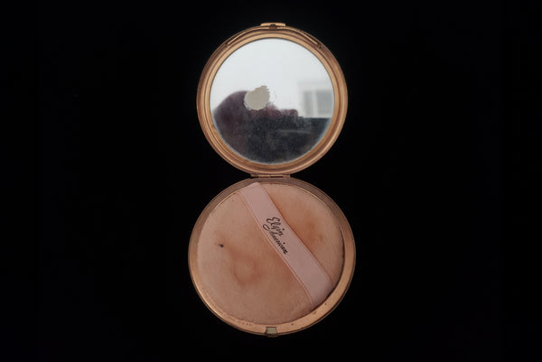 Horizontal open view of 1930s vintage Art Deco black and white enamel round gold metal mesh make-up compact by Elgin. Showing an age spot on the mirror.
