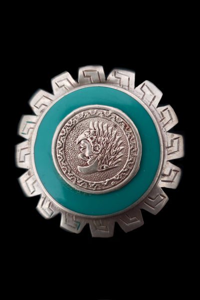 Vertical front view of 1960s vintage round silver and turquoise enamel upside down man in bird costume brooch/pendant. Hecho en Mexico.