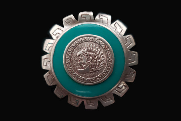 Horizontal front view of 1960s vintage round silver and turquoise enamel upside down man in bird costume brooch/pendant. Hecho en Mexico.