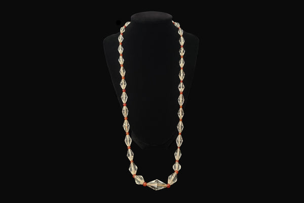 Horizontal view of 1920s vintage graduated bicone clear crystal bead necklace with orange amber colored round glass spacers. Showing the necklace on a display.