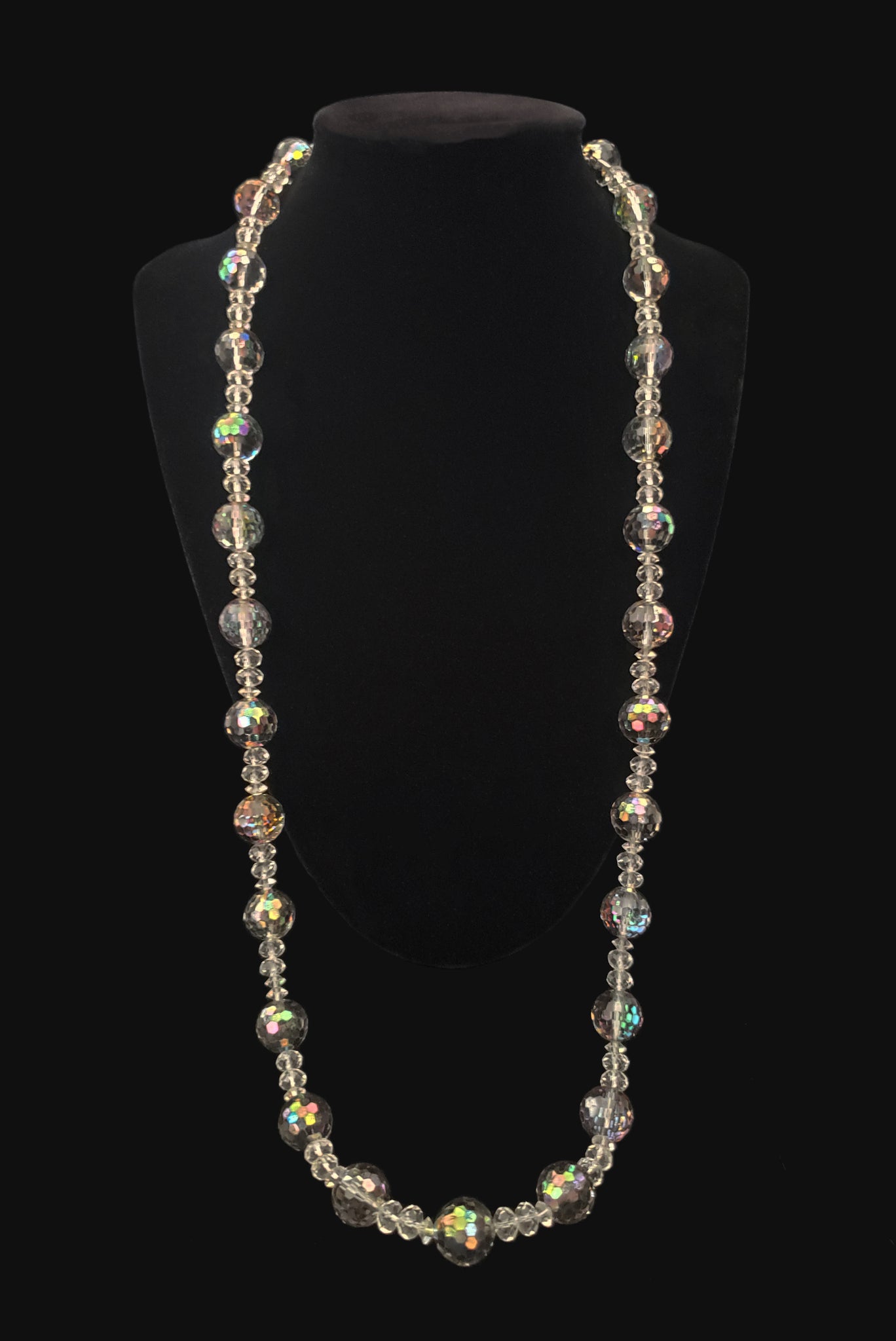 Vertical view of 1980s vintage iridescent gray and clear crystal long beaded necklace. Showing the necklace on a display stand.