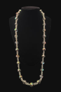 Vertical view of 1980s vintage iridescent gray and clear crystal long beaded necklace. Showing the necklace on a display stand.