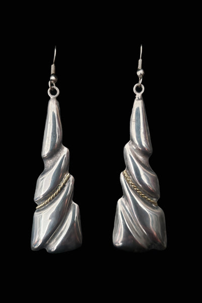 Vertical front view of 1980s vintage Taxco two-tone 925 sterling silver and brass triangular fish hook pierced drop earrings.