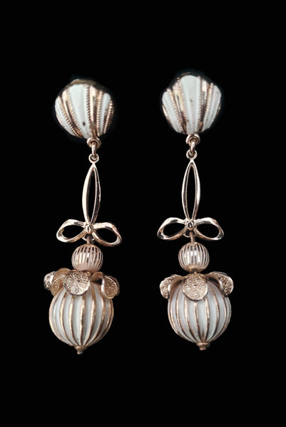 Vertical front view of 1960s vintage champagne gold metal and white painted beaded drop clip-on earrings by Globus.