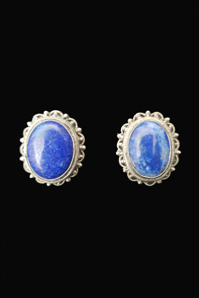Vertical front view of 1950s vintage blue lapis lazuli oval cabochon and silver filigree screwback earrings.