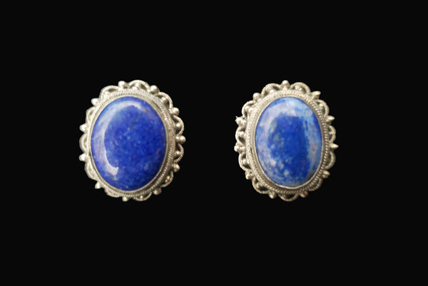 Horizontal front view of 1950s vintage blue lapis lazuli oval cabochon and silver filigree screwback earrings.