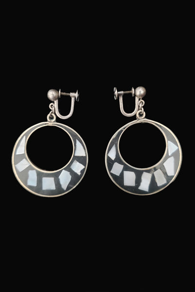 Vertical side view of 1950s vintage alpaca silver and white abalone shell inlaid in black drop hoop screw back earrings.