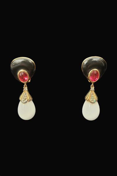 Vertical front view of 1980s vintage black enamel, oval pink rhinestones, clear rhinestones, white plastic drop, and gold tone metal pierced lever back earrings, by Nina Ricci.