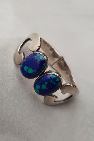 Vertical perspective view of 1980s vintage Taxco 925 sterling silver and blue green azurite oval cabochon clamper bracelet.