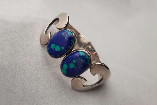 Horizontal perspective view of 1980s vintage Taxco 925 sterling silver and blue green azurite oval cabochon clamper bracelet.