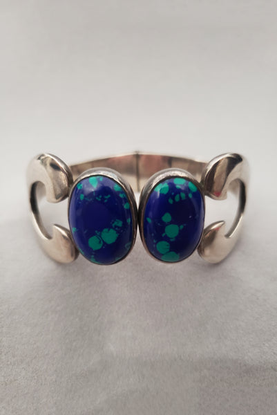 Vertical front view of 1980s vintage Taxco 925 sterling silver and blue green azurite oval cabochon clamper bracelet.