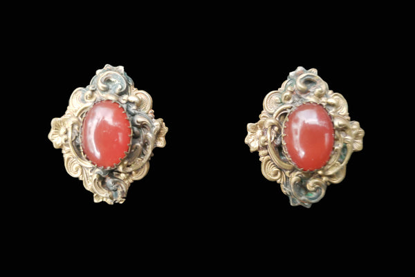 Horizontal front view of 1940s vintage rust carnelian oval cabochon in a brass filigree setting unpierced screw back earrings.
