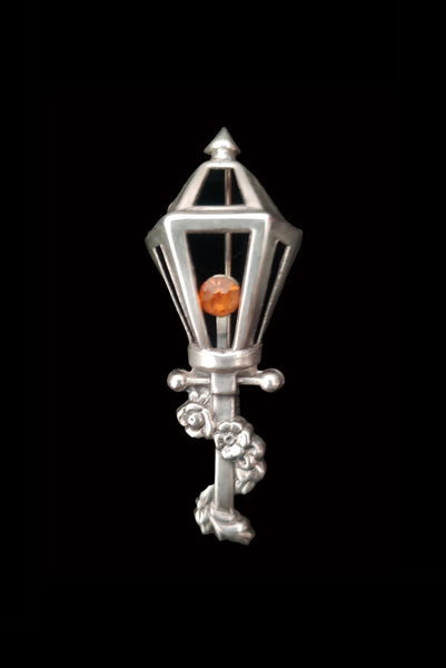 Vertical front view of 1950s vintage 925 sterling silver and orange rhinestone lamppost brooch by Lang.