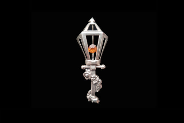 Horizontal front view of 1950s vintage 925 sterling silver and orange rhinestone lamppost brooch by Lang.