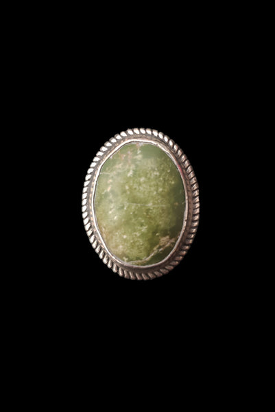 Vertical front view of 1960s vintage southwestern silver and oval green cabochon mid century ring, size 6.25.