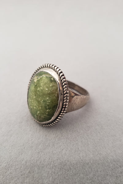 Vertical perspective view of 1960s vintage southwestern silver and oval green cabochon mid century ring, size 6.25.