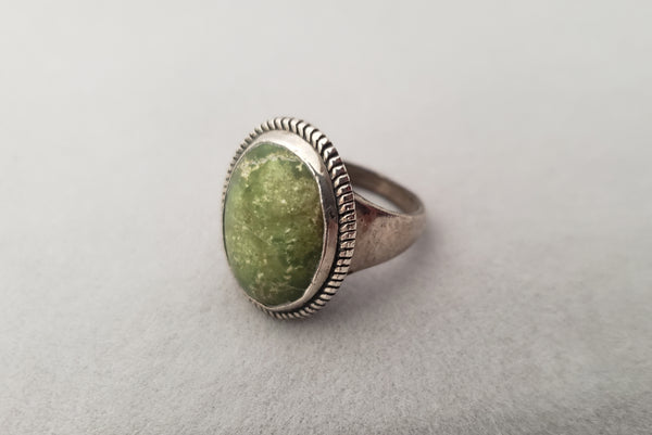 Horizontal perspective view of 1960s vintage southwestern silver and oval green cabochon mid century ring, size 6.25.