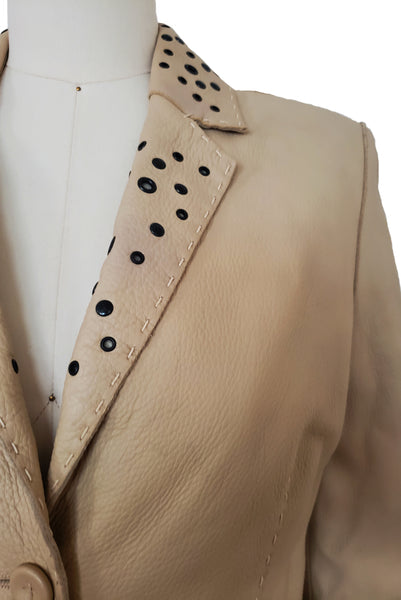 Detail view of 1990s topstitched metal eyelet and stud embellished buff leather blazer by Donald Pliner, extra small to small, showing the topstitched collar embellished with black eyelets and studs.