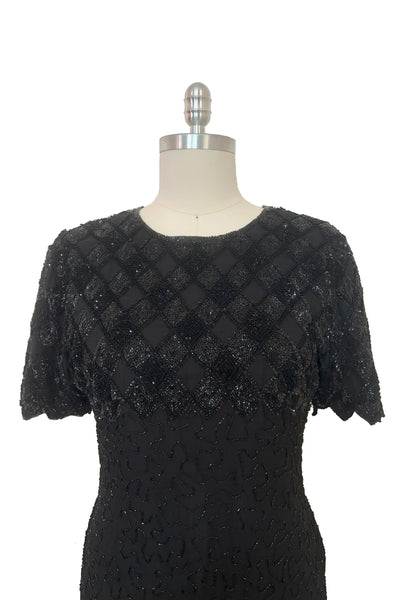 Bodice front view of 1980s vintage diamonds black beaded and sequin silk chiffon crew neck, short sleeve, fitted knee length cocktail dress by Laurence Kazar, size medium to large. Showing a close-up of the sequin diamond pattern on the bust & shoulders, and the sawtooth hem on the sleeves.