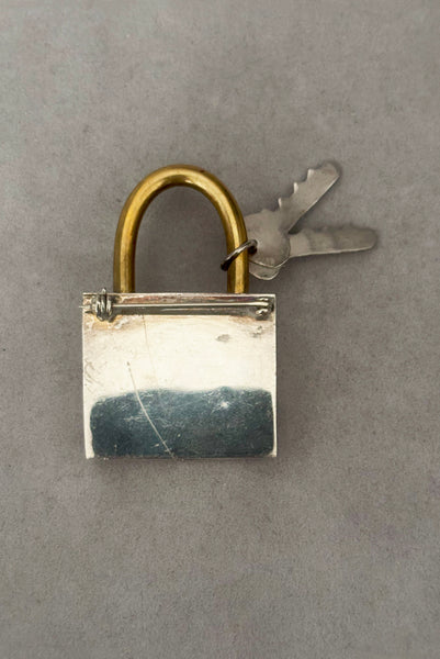 Vertical back view of 1960s vintage Mexican 925 sterling silver and brass hollow padlock and key two tone statement brooch.