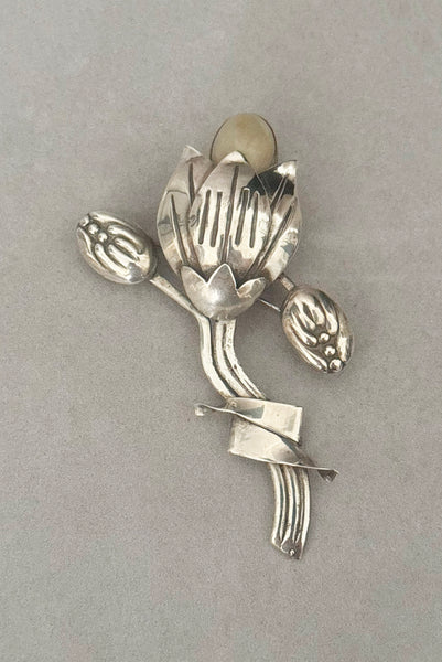 Vertical front view of 1930s vintage Mexican 925 sterling silver flower statement brooch with oval cream cabochon stone.