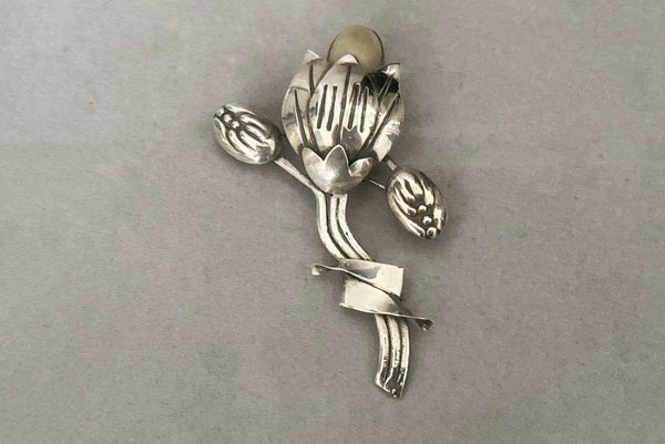 Horizontal front view of 1930s vintage Mexican 925 sterling silver flower statement brooch with oval cream cabochon stone.