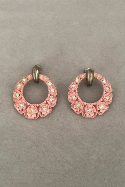 Vertical front view of 30s vintage pink floral carved celluloid and rhinestone silver tone screw back hoop earrings.
