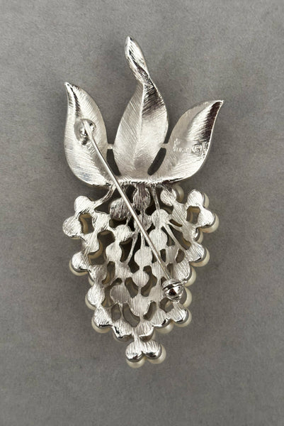 Vertical back view of 1960s vintage Crown Trifari white pearl silver tone grape cluster brooch and clip-on earrings jewelry set. Showing the brooch alone.