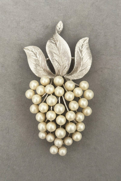 Vertical front view of 1960s vintage Crown Trifari white pearl silver tone grape cluster brooch and clip-on earrings jewelry set. Showing the brooch alone.
